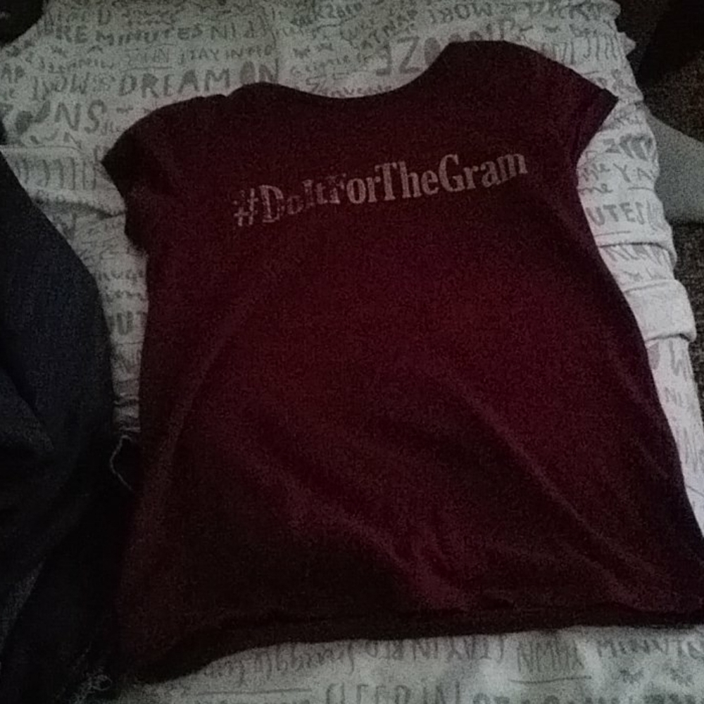 A burgundy, shirt  with gold printed letters